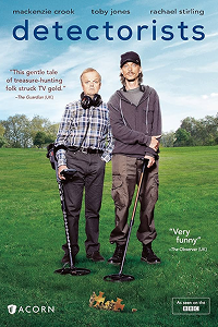 A poster of Detectorists. It features two men standing in a green field with metal detectors, with the title "detectorists" at the top and quotes about the show on the sides.